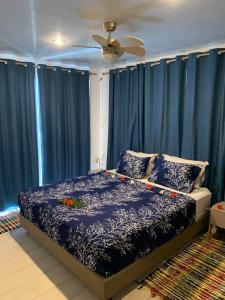 Un dormitorio con cortinas azules y una cama con flores. en A TOMO MAI Homestay en Faaa