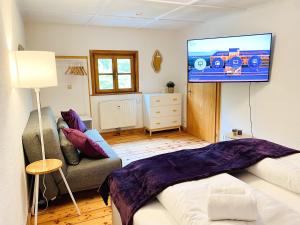 ein Wohnzimmer mit einem Flachbildfernseher an der Wand in der Unterkunft Belisima Apartments I Ferienwohnungen Fischbachau - Breitenstein I Region Schliersee I Historisch & Cozy mit Bergblick I 2 Schlafzimmer I Waschmaschine I Parkplatz I Nähe Supermarkt in Fischbachau