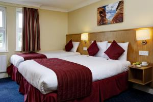 a hotel room with two beds with red sheets at Best Western London Highbury in London