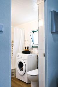 een badkamer met een wasmachine en een toilet bij Casa da Avó Couta in Angra do Heroísmo