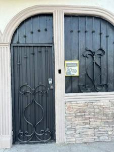 zwei schwarze Türen an einem Gebäude mit einem Schild drauf in der Unterkunft Casa en Mexicali in Mexicali