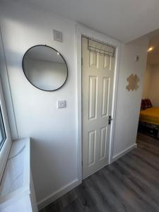 un couloir avec un miroir et une porte blanche dans l'établissement Enjoy the comfort at beautiful studio, à Luton