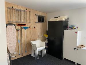 a room with a black refrigerator and a white chair at Mountain View Cottage in Arrowtown