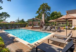 a swimming pool with chairs and umbrellas at Half Moon Bay Lodge in Half Moon Bay