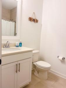 a white bathroom with a toilet and a sink at 5 Star 4/3 sleeps 16 with Arcade GAME ROOM & POOL! in Orange Beach