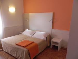 a small bedroom with a bed with an orange wall at Affittacamere Via Mazzini in Stresa