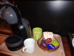 a coffee pot and a bowl of cookies and a coffee cup at Monte Verde Inn Suítes com Hidromassagem dupla in Monte Verde