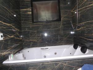 y baño con bañera y paredes de mármol negro. en Monte Verde Inn Suítes com Hidromassagem dupla, en Monte Verde