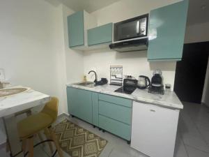 a small kitchen with blue cabinets and a microwave at Studio Ça Mplait in Cayenne