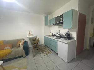 a kitchen with blue cabinets and a couch in a room at Studio Ça Mplait in Cayenne +2 photos
