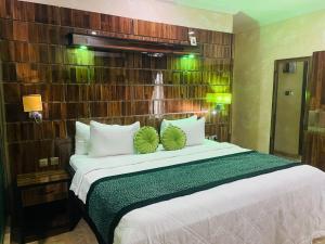 a bedroom with a bed with two green pillows on it at St. Regis Hotel & Resort - Benin City in Benin City