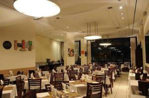 a dining room with white tables and chairs and lights at 701 - Flat Temporada em Goiania-proximo ao Parque Areião in Goiânia