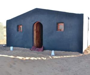 a blue building with a wooden door and two windows at Mhamid Tours in Mhamid