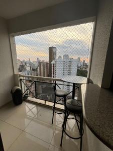 a balcony with a table and chairs and a large window at 1810 - Flat para temporada em Goiania-proximo ao Parque Areião in Goiânia