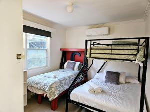 sypialnia z 2 łóżkami piętrowymi i oknem w obiekcie Cheerful 3 bedroom home in the centre of town w mieście Shepparton