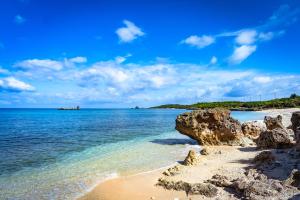 a beach with rocks and the ocean on a sunny day at Black Diamond 宮古島 in Karimata