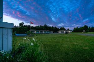 a green field with a canadian flag and a cloudy sky at North Rustico Harbour Inn in North Rustico