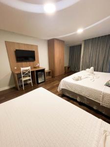 ein Hotelzimmer mit 2 Betten und einem Flachbild-TV in der Unterkunft Athos Hotel in Teresópolis