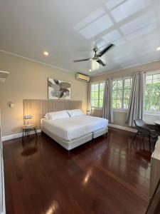 1 dormitorio con cama blanca, suelo de madera y ventanas en Casa Randa, en Panamá