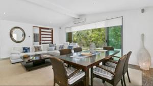 uma sala de jantar com uma mesa e cadeiras e um sofá em 9 Depper St - Upper Level Only em Sunshine Beach