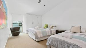 um quarto branco com 2 camas e uma cadeira em 9 Depper St - Upper Level Only em Sunshine Beach