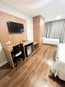 ein Hotelzimmer mit einem Schreibtisch und einem Bett sowie einem Zimmer in der Unterkunft Athos Hotel in Teresópolis
