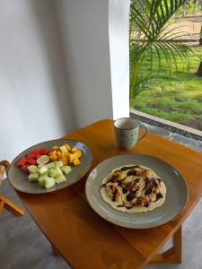 una mesa con dos platos de comida y fruta. en Rumah Markisa Batukaras en Batukaras