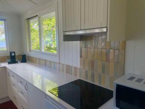 a kitchen with a white counter top and two windows at Flinders Seaside Cottage in Brighton