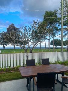 a wooden table and chairs with a fence and the ocean at Flinders Seaside Cottage in Brighton