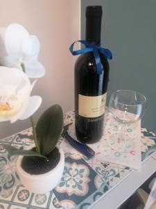 una botella de vino y una planta sobre una mesa en B&B- La Casa Blu- Forum di Assago, Humanitas, Milanofiori, IEO, en Rozzano