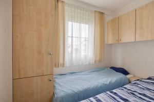 a bedroom with a bed and a window and cabinets at Polderpark 190 in Nieuwpoort