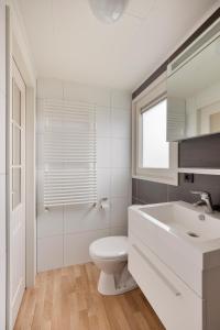 a white bathroom with a toilet and a sink at Polderpark 190 in Nieuwpoort
