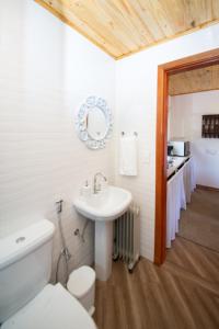a white bathroom with a sink and a toilet at Chalé Lírio Cachoeira do Vale in Monte Verde