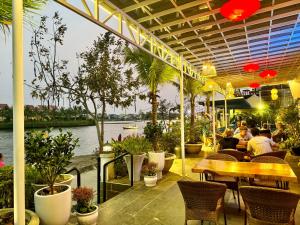 um restaurante com pessoas sentadas em mesas e plantas em Riverside White House Hotel em Hoi An