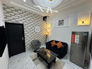 - un salon avec un canapé noir et un réfrigérateur dans l'établissement Rossoul Appartement, à Cotonou