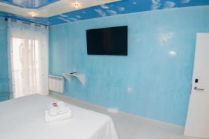 Habitación azul con cama y TV en la pared en Hostal Palacio Madrid, en Madrid