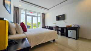 Dormitorio con cama, escritorio y TV en Riverside White House Hotel en Hoi An