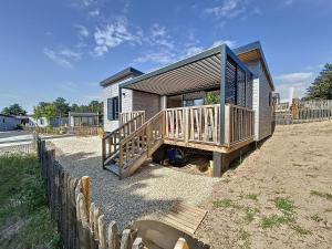 une petite maison avec une terrasse en bois et une clôture dans l'établissement Chalet cozy à Jullouville - 4 pers, piscine chauffée, proche plage et commerces - FR-1-361-538, à Jullouville