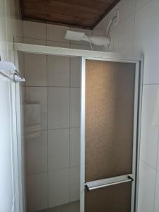 La salle de bains est pourvue d'une douche avec une porte coulissante. dans l'établissement Pousada central Vino e Leta, à Grão Pará