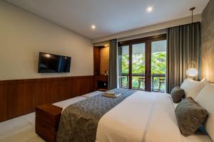 a bedroom with a large bed and a tv at JAPA Suites & Villas in Ubud
