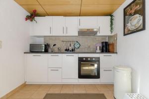 a kitchen with white cabinets and a stove at Bungalow Lieschen für 3 Personen und eigener Terrasse in Kühlungsborn