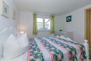 a bedroom with a bed with a floral bedspread and a window at Bungalow Lieschen für 3 Personen und eigener Terrasse in Kühlungsborn