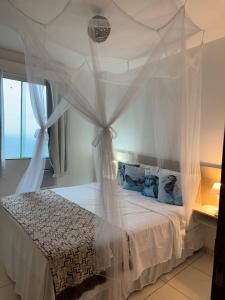 a bedroom with a white bed with a canopy at Flats Bela Vista para o Mar in Macaé