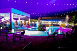 a restaurant with tables and a swimming pool at night at LE VAHINÉ Eco-RESORT in Toliara