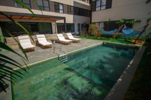 einen Pool mit Stühlen und einer Hängematte neben einem Gebäude in der Unterkunft Blend Coliving One - 3b in Ribeirão Preto