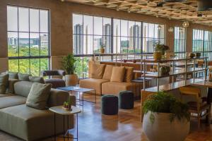 eine Lobby mit Sofas, Tischen und großen Fenstern in der Unterkunft Blend Coliving One - 3b in Ribeirão Preto