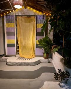 un palco con tenda gialla in una stanza con piante di Casa Acquamarina ad Atins