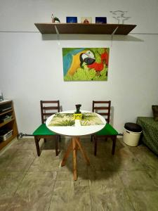 une table avec deux chaises et un tableau sur le mur dans l'établissement Studio no Largo da Carioca - Rio de Janeiro, à Rio de Janeiro
