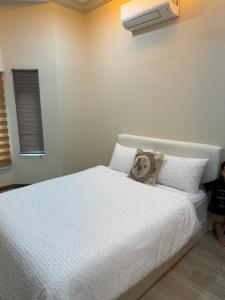 a bedroom with a white bed with a child standing next to it at Rumah Tuma in Shah Alam