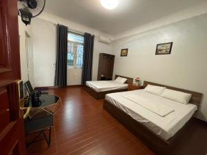 una camera con 2 letti, una scrivania e una TV di Hotel Me Kong 2 a Ha Long